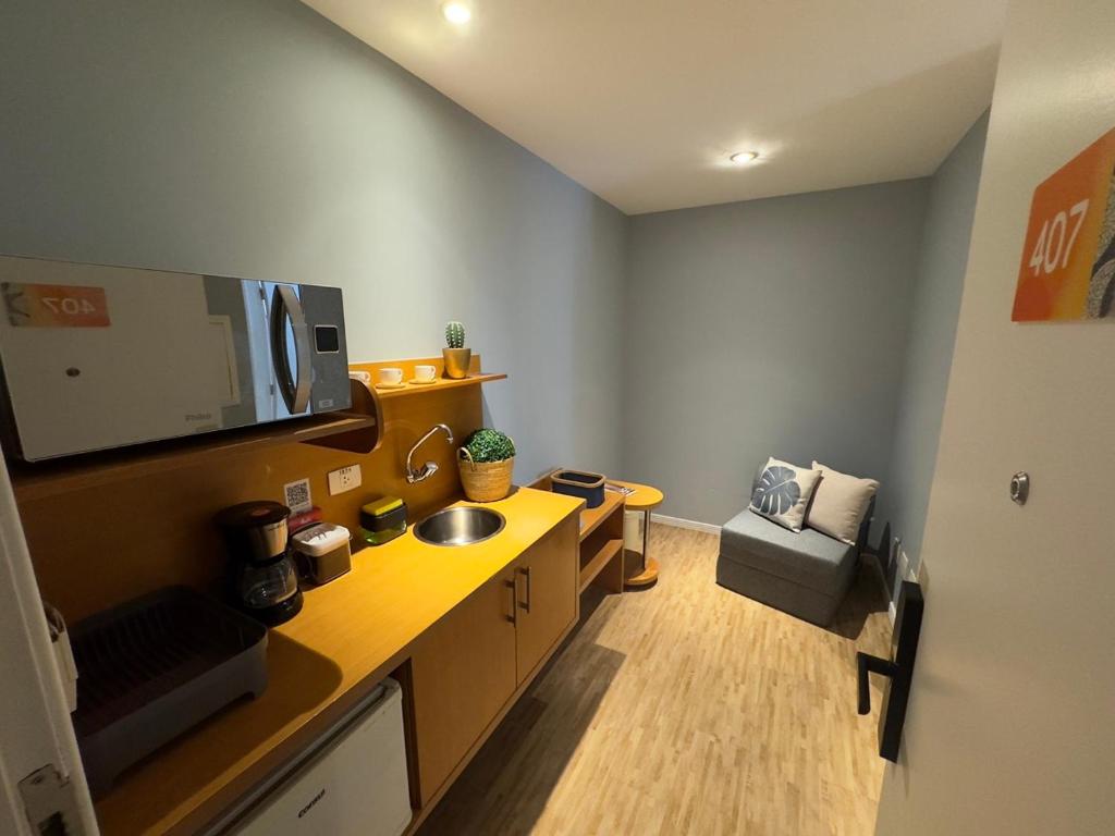 a room with a kitchen with a sink and a tv at Conforto e Praticidade Apartamento até 3 no Batel in Curitiba