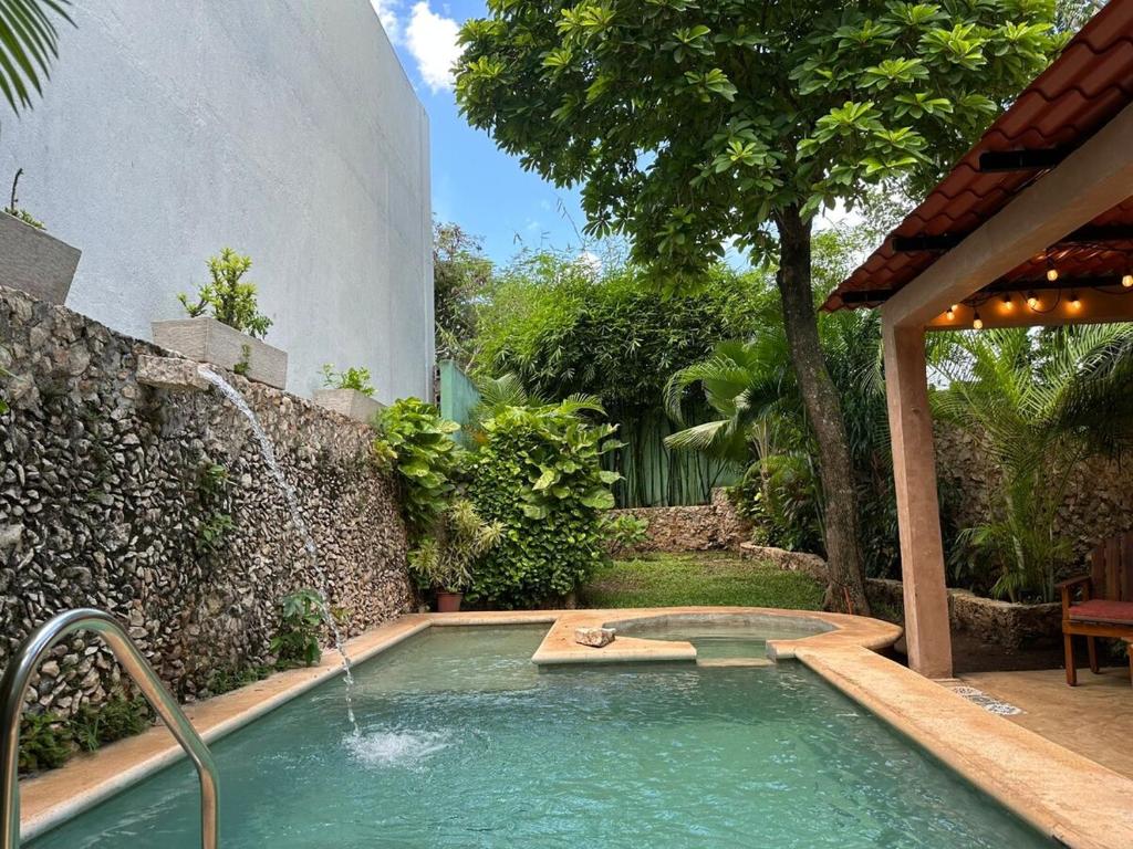 a swimming pool with a fountain in a backyard at Casa Yuya in Valladolid