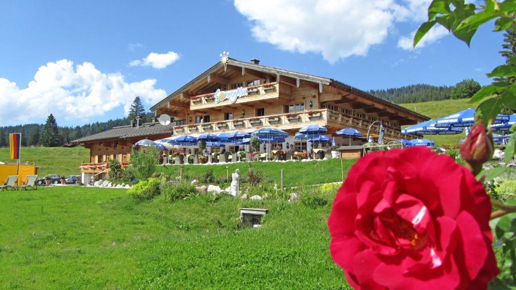 un edificio con una flor roja delante de él en Winklmoos Sonnenalm, en Reit im Winkl