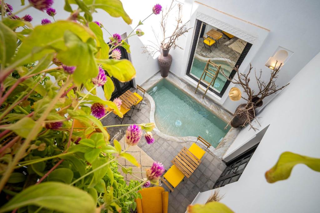 una vista sul soffitto di una piscina con sedie e fiori di Riad Come & Va Medina a Marrakech