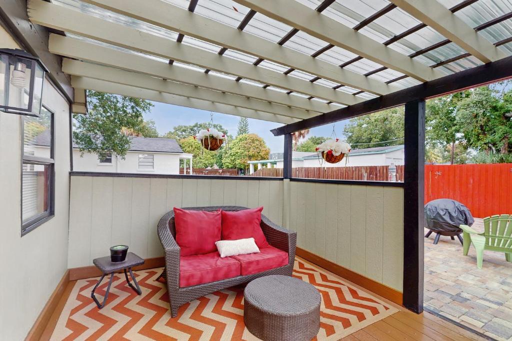 un patio con una sedia rossa e un pergolato di Suite West C a Tampa