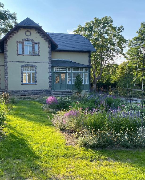 a house with a garden with flowers in the yard at Design Villa Uckermark mit riesigem Garten in Ferdinandshof