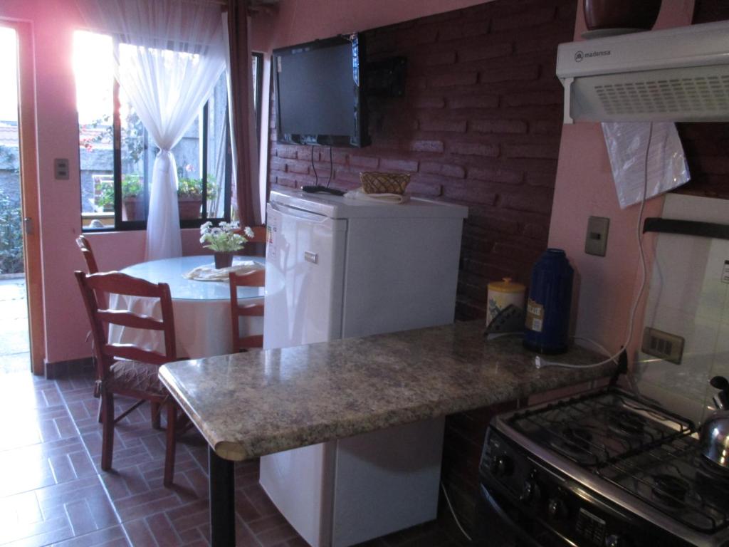 a kitchen with a white refrigerator and a table at Hostal Julia in El Quisco