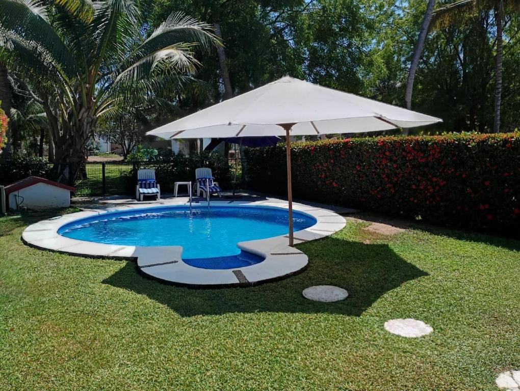 曼萨尼约La Casa del Mar, Club Santiago with a private pool的一个带遮阳伞和两把椅子及一张桌子的游泳池