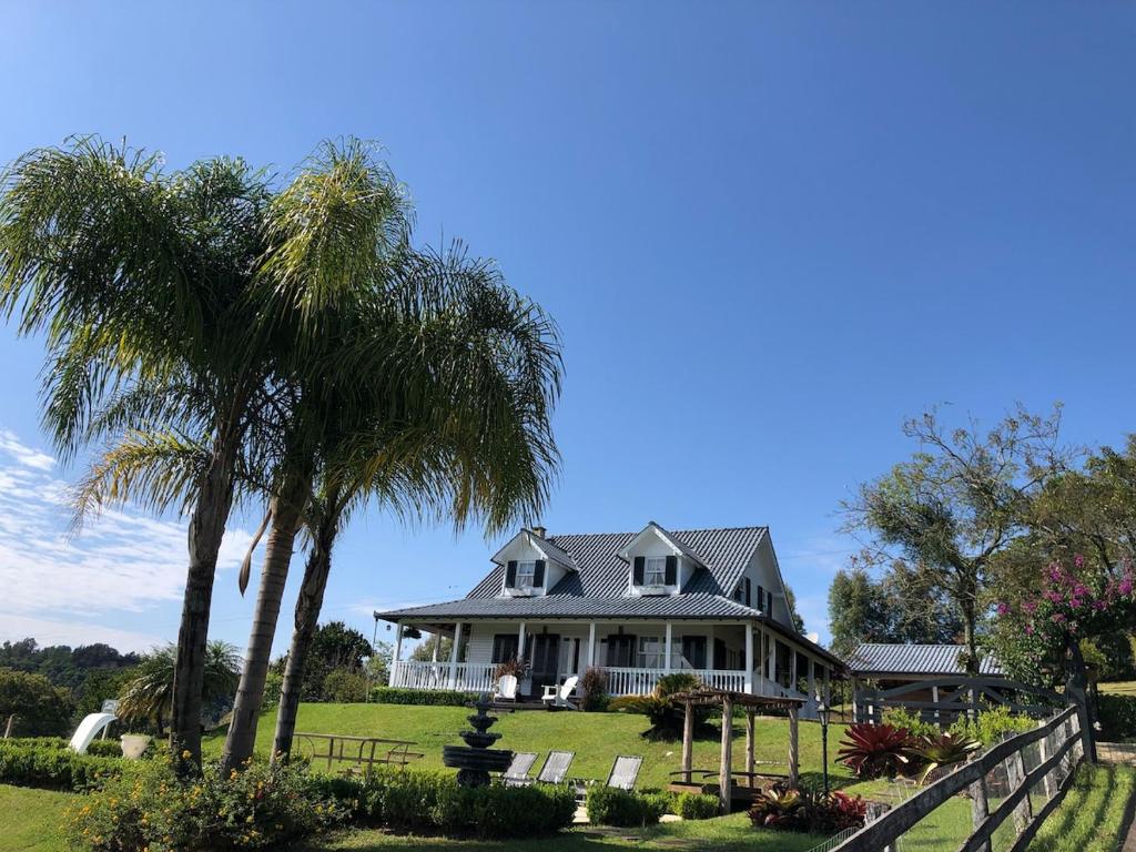 una casa grande con palmeras y una valla en Rancho SF Casa Texana, en Novo Hamburgo