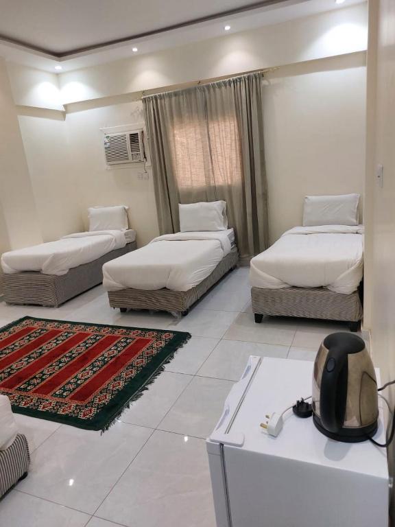 a living room with three beds and a table at عمارة كنوز الحديثة in Al Madinah