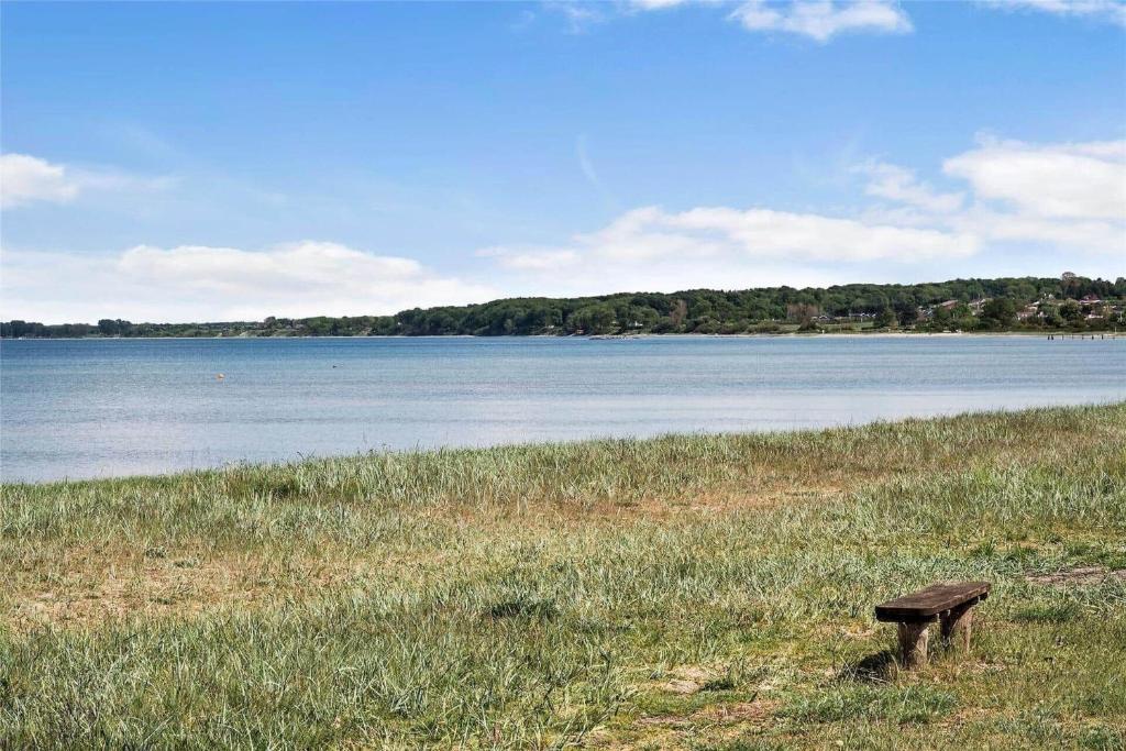 a bench sitting in the grass near a body of water at FY150-Middelfart-Vegavej-24 in Middelfart