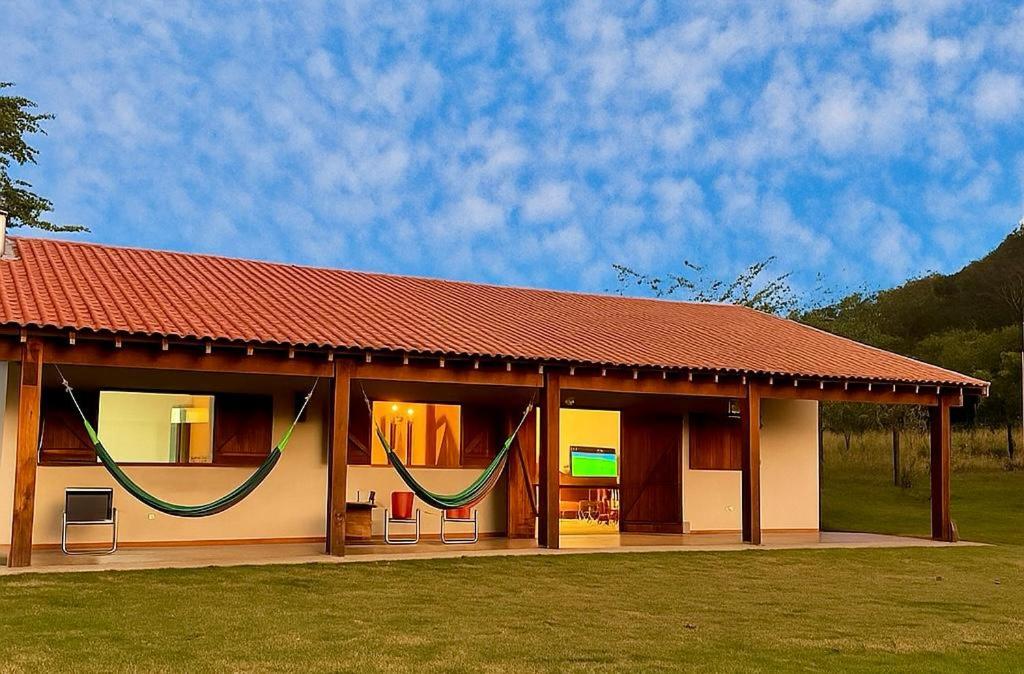 a house with a red roof with hammocks on it at Estância Vó Maria em Bodoquena in Bodoquena