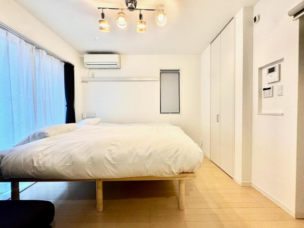 a bedroom with a bed with white sheets and a window at Capital Shimbashi 101, Studio in Tokyo