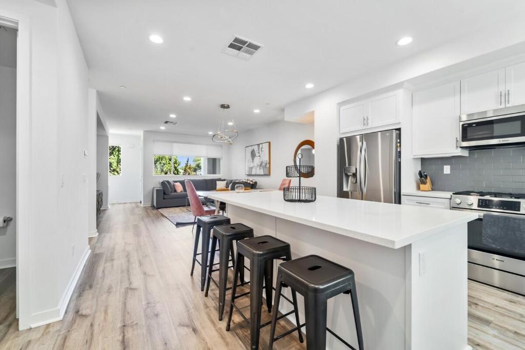a kitchen with white cabinets and a counter with stools at NoHo Modern Townhouse with Gorgeous Rooftop in Van Nuys