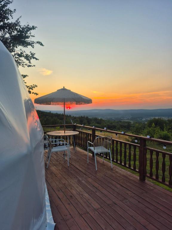 a table and chairs on a deck with an umbrella at Glamping Agro Marzenie in Krajno Pierwsze