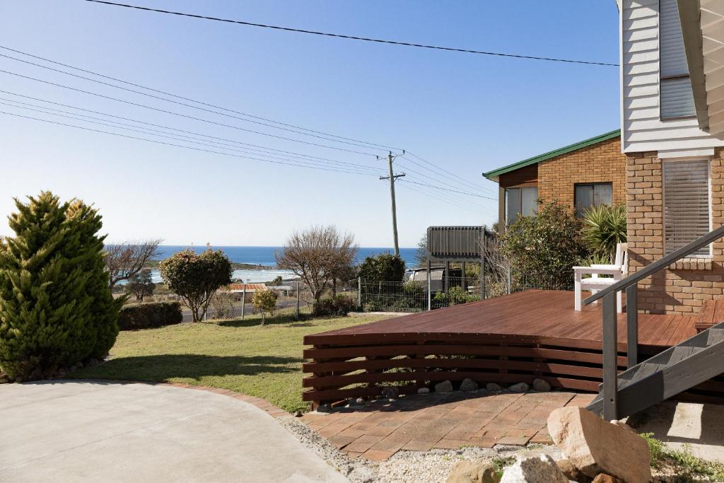 a house with a wooden deck with a view of the ocean at Travellers Rest Bicheno in Bicheno