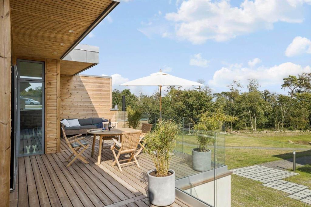 a wooden deck with a table and an umbrella at 5607-Svaneke-Mollebakken-8-P in Svaneke