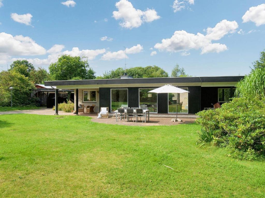 a house with a patio and a grass yard at 8 person holiday home in Asnæs in Asnæs