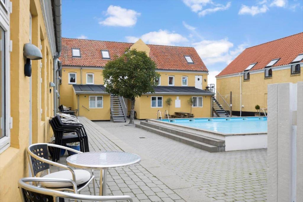 a patio with a table and chairs next to a swimming pool at 5645-Gudhjem-Broddegade-14-lejl-13 in Gudhjem