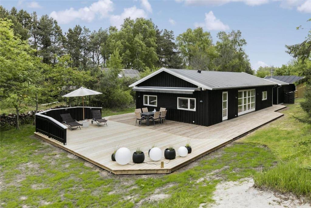 ein schwarzes winziges Haus auf einer Holzterrasse in der Unterkunft 1435 Aakirkeby - Ædjavejen 10 in Vester Sømarken