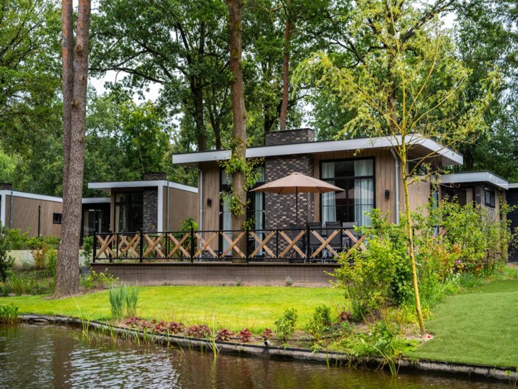 ein Haus mit einem Teich davor in der Unterkunft Modern Lakeview Cottage in Veluwe in Hoenderloo