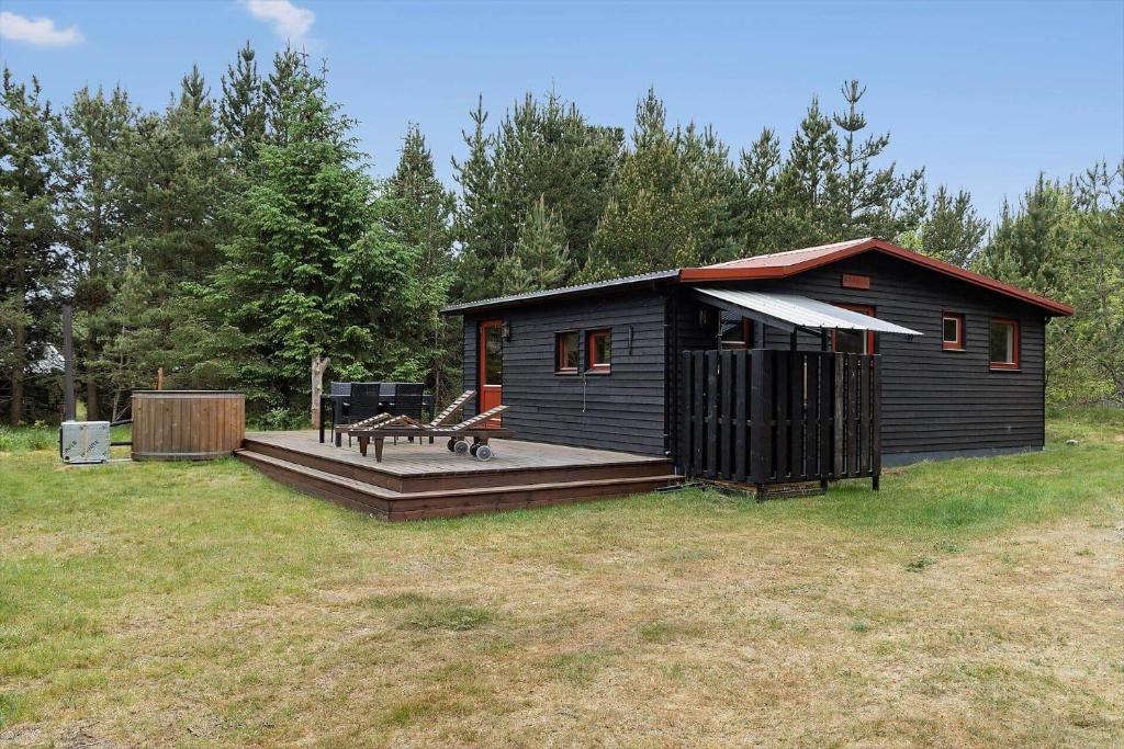 a small cabin with a deck and a bench at HA374-Saeby-Klitvej-12 in Sæby