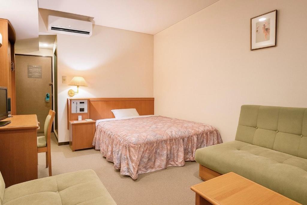 Una habitación de hotel con una cama, un sofá y una silla. en Matsue Universal Hotel, en Matsue