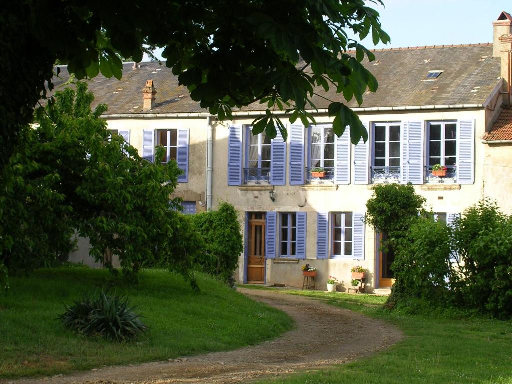 a house with blue shutters and a dirt road at B&B Girolles les Forges in Girolles