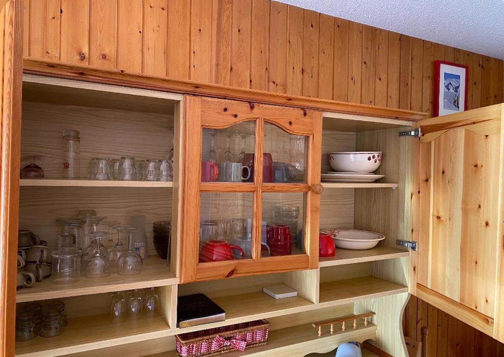 a wooden cabinet filled with lots of dishes at Studio la mongie de 33m2 à 150 m des pistes in La Mongie