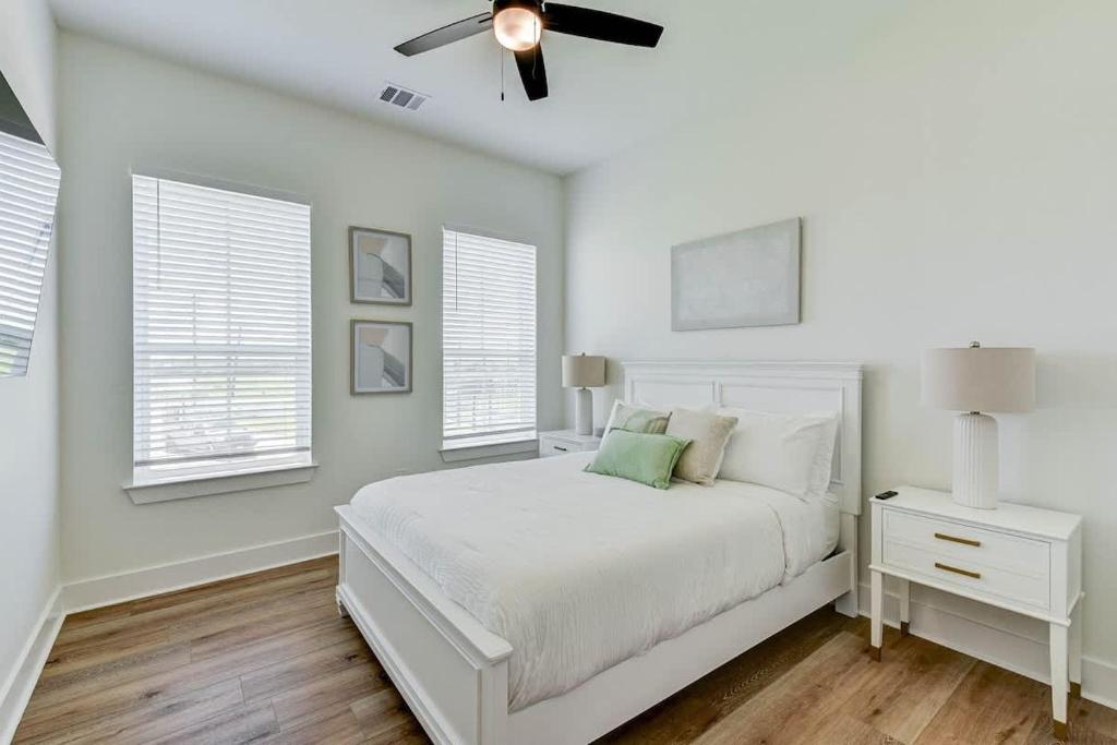 a white bedroom with a bed and a ceiling fan at Cozy Villa Walk to Beach in Galveston