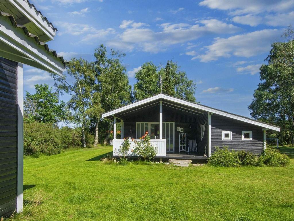 a small house with a porch on a lawn at 6 person holiday home in Glesborg in Glesborg