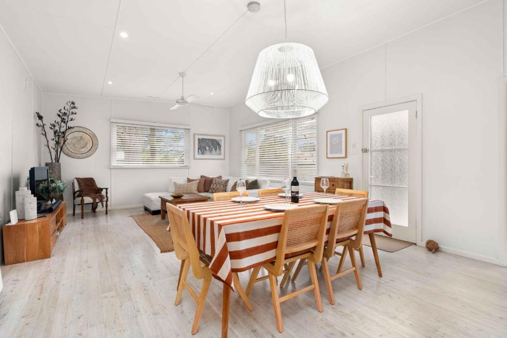 una sala da pranzo e un soggiorno con tavolo e sedie di Whitewash Cottage by Experience Jervis Bay a Huskisson