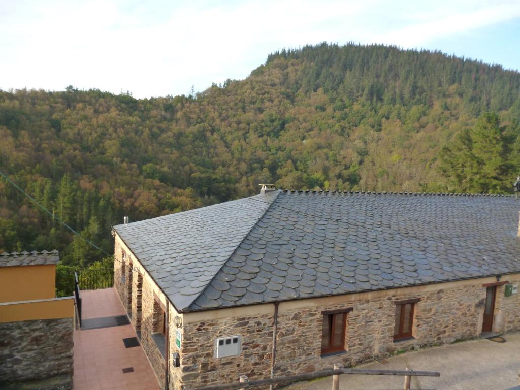 un edificio con techo de pizarra con una montaña en el fondo en Apartamentos Rurales Veredas, en Santa Eulalia de Oscos