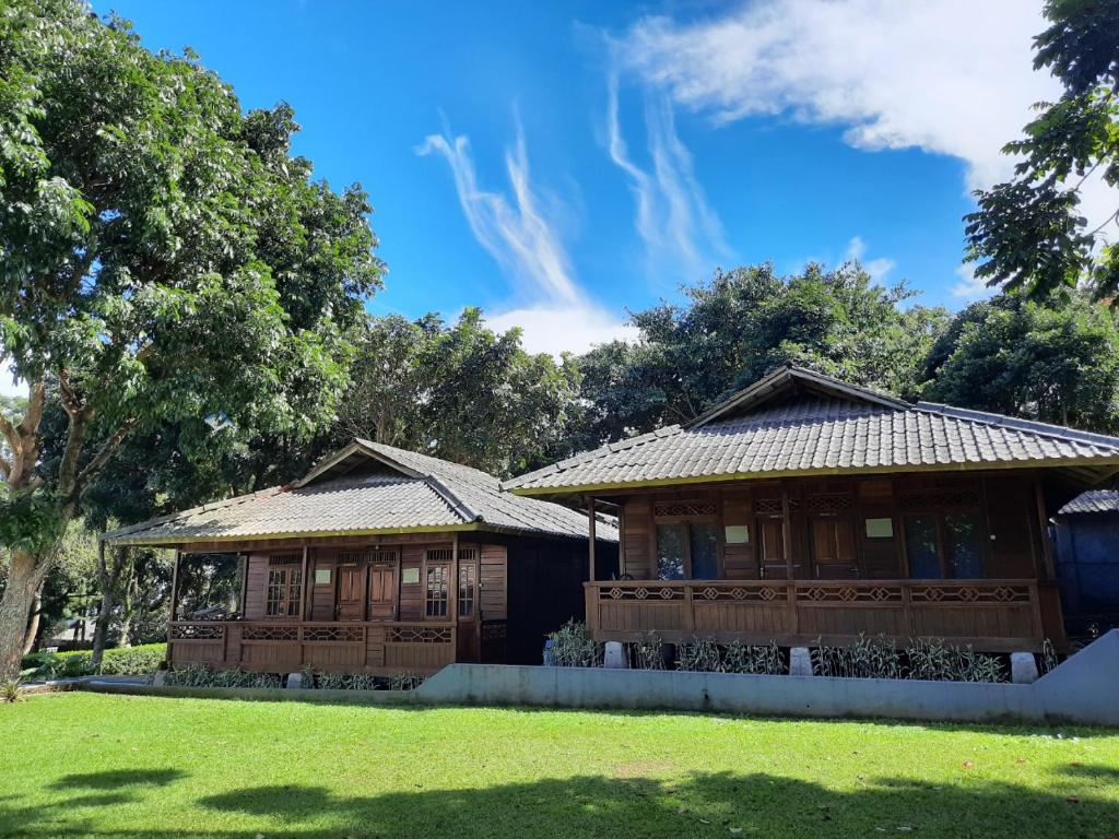 deux bâtiments en bois avec des arbres en arrière-plan dans l'établissement Tjapoeng Resort Pancawati, à Ciherangsating