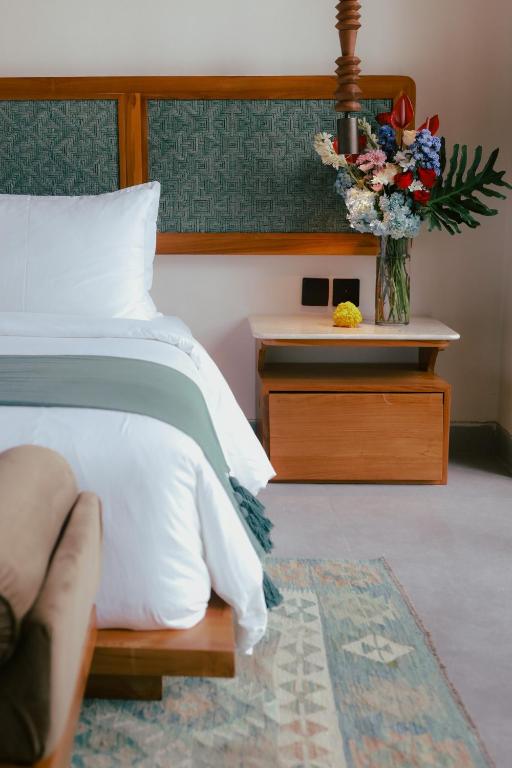 a bedroom with a bed and a table with a vase of flowers at Leafy Riverbank in Tabanan