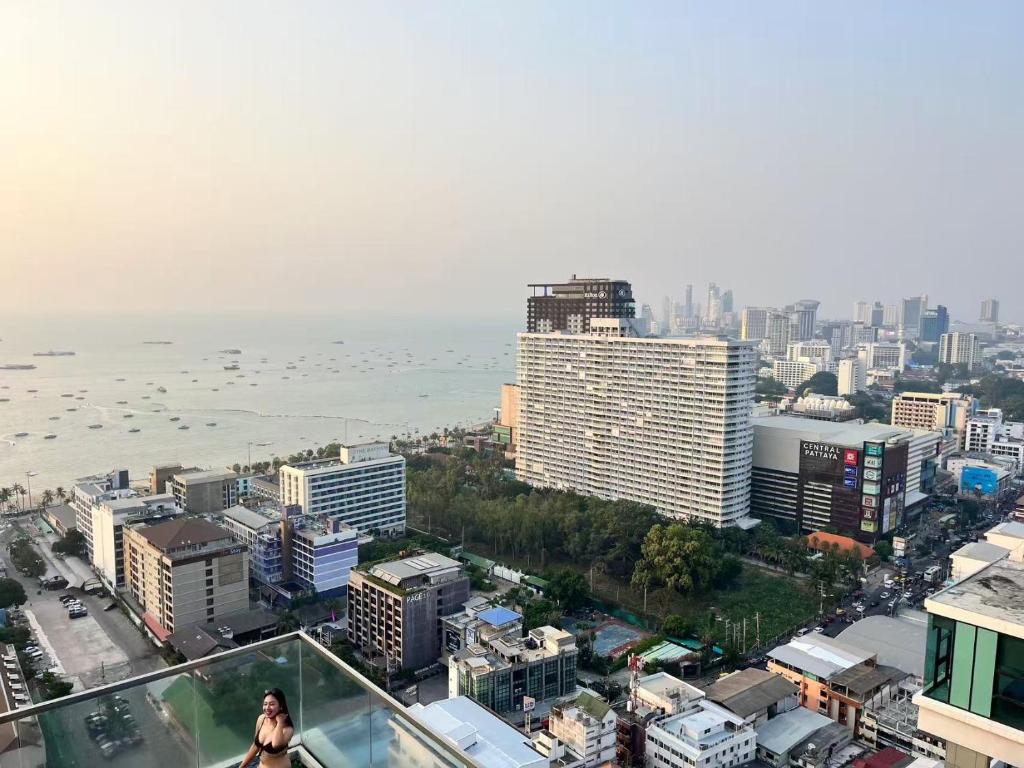 a woman walking on top of a building overlooking a city at The Base Pattaya Seaview Condo in Pattaya Central