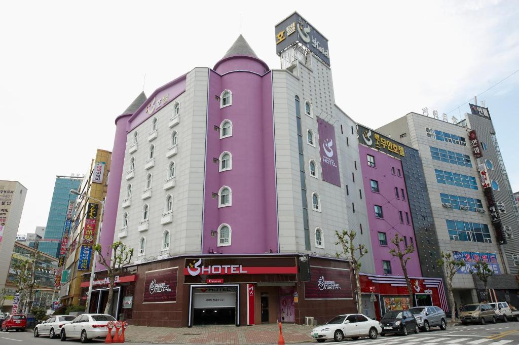 een roze gebouw met auto's geparkeerd in een stad bij S Hotel in Gwangju