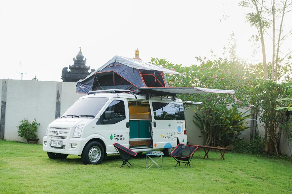 a white van parked in a yard with a tent on top at Campervan Rental Bali - Camper Republik in Dalung