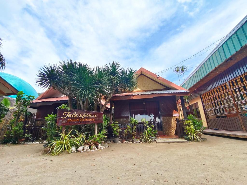 a restaurant with a sign in front of a building at Telesfora Beach Cottage in El Nido