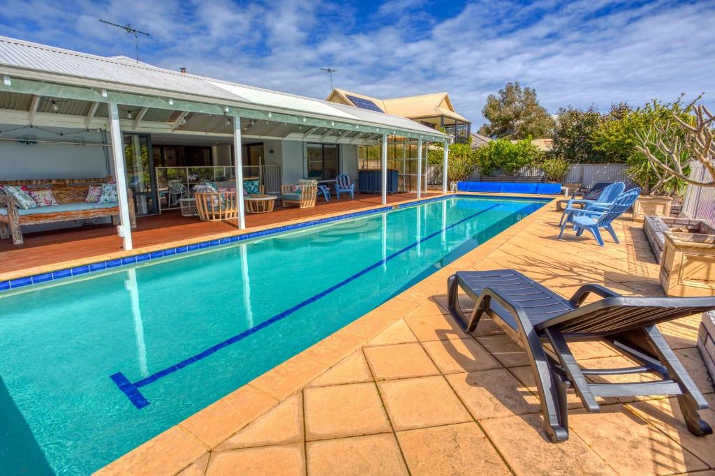 a swimming pool with chairs and a house at Pool and Putt Paradise in Dunsborough