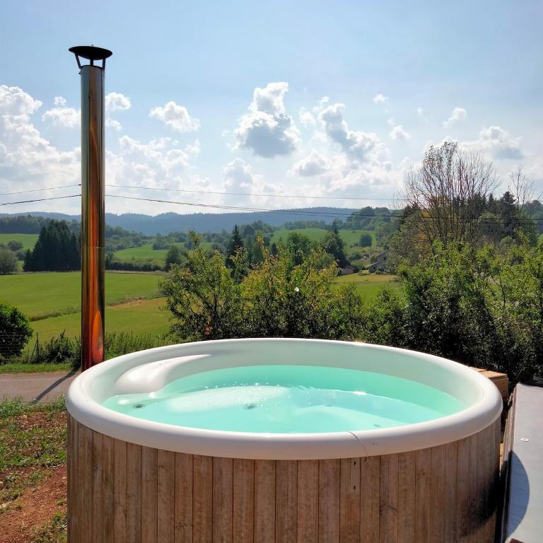 a jacuzzi tub with a view of the countryside at Le bain nordique du lynx boréal in Entre-Deux-Monts