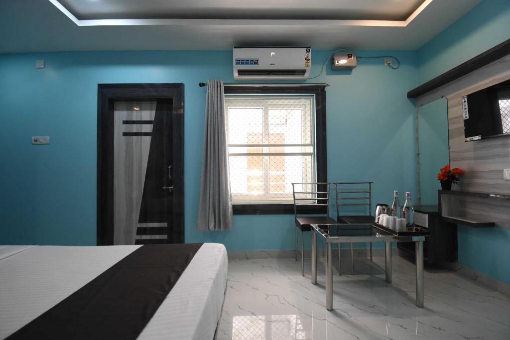 a blue room with a bed and a table and a window at Hotel O Prince Residency in Bhubaneshwar