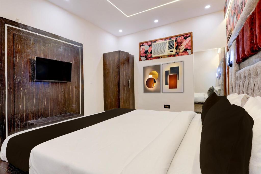 a bedroom with a white bed and a tv at Super Hotel O JC Luxury Hotel in Kurukshetra