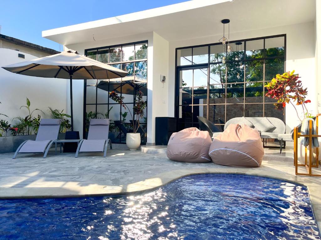 a swimming pool with two bean chairs and an umbrella at Tres Villas Kuta in Kuta Lombok