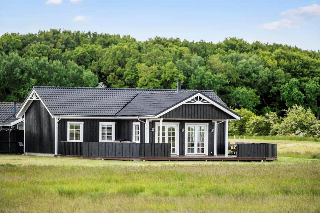 ein kleines Haus mit einem schwarzen Dach auf einem Feld in der Unterkunft OH362 Storvorde - Kongeørnen 74 in Storvorde