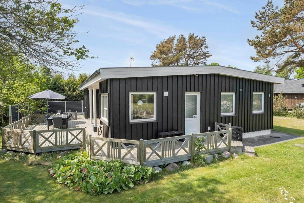 ein schwarzes kleines Haus mit einer Terrasse in einem Hof in der Unterkunft OH507 Hadsund - Ved Fruerlund 1 in Hadsund