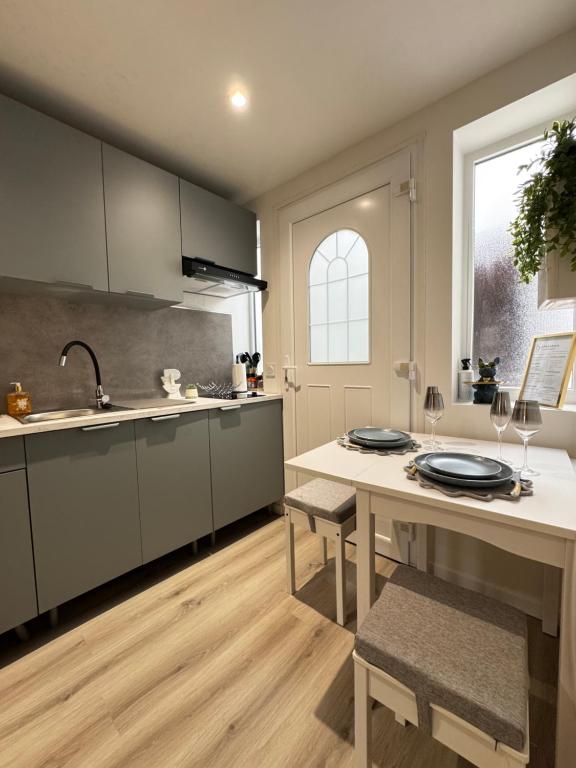 a kitchen with a sink and a table with chairs at Maisonnette neuve, centre-ville, 20mn de Paris in Herblay