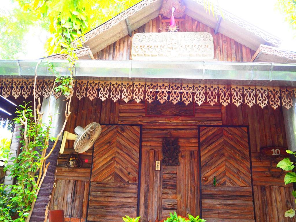 una puerta de madera de una casa con una cortina encima en Three J Guesthouse en Kamphaeng Phet