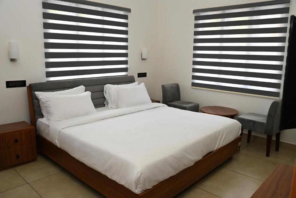 a bedroom with a large white bed and a chair at Wayanad Farm Heritage in Sultan Bathery
