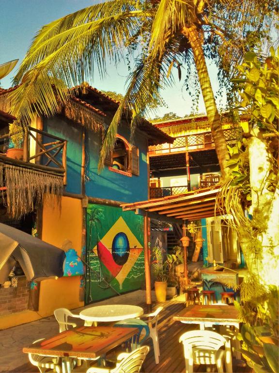 a patio with tables and chairs and a palm tree at Suítes do Caboclo in Ilhabela