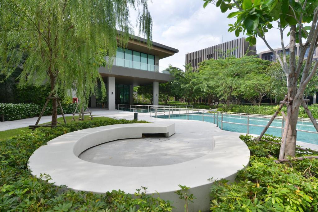 A garden pool is framed by a curved concrete seating feature and mature trees.