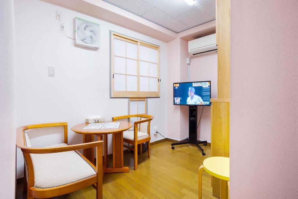 a room with a table and chairs and a tv at Sunflower Hotel 703, Osaka, Namba & Shinsaibashi in Osaka