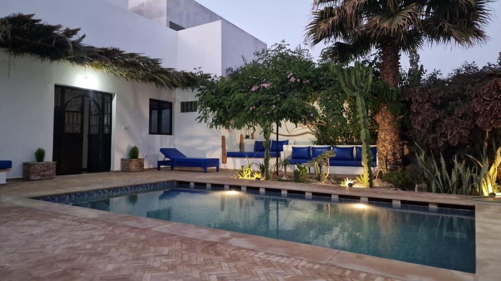 a swimming pool in front of a house with blue furniture at Dar D'art Luz Galerie Boutique Guest house in Al Ghar