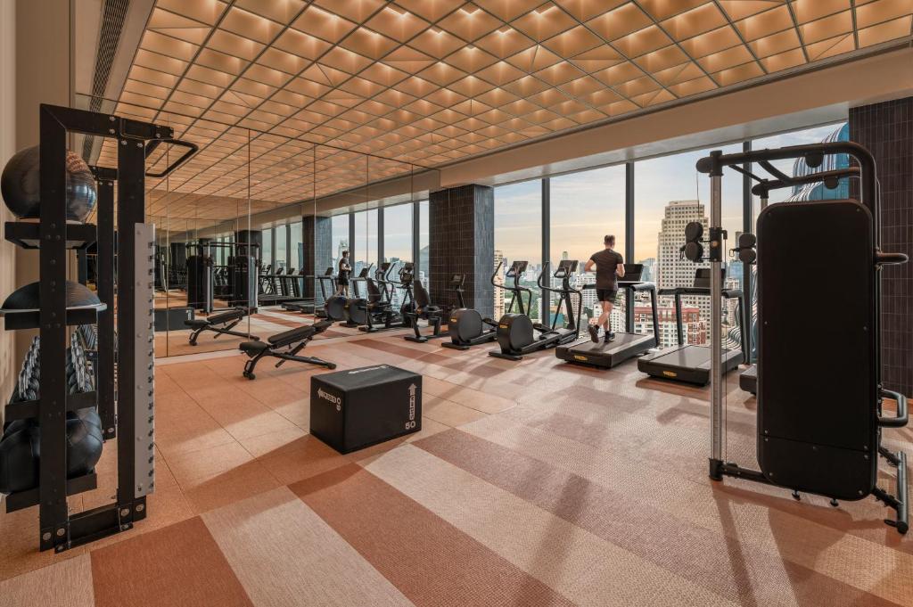 A bright glass-walled fitness room with cardio and strength equipment above the city.